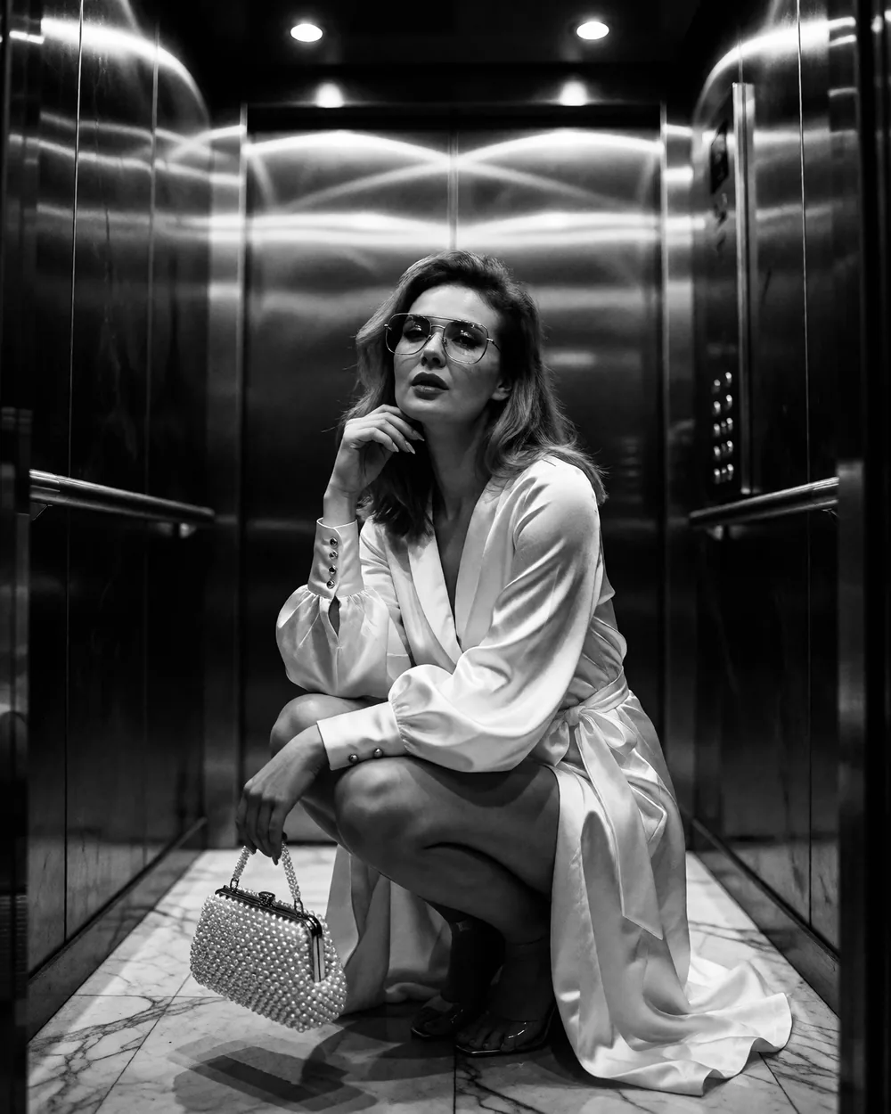 Ksenia Błażyca w jasnej satynowej sukience z torebką z perełek — czarno-biały portret